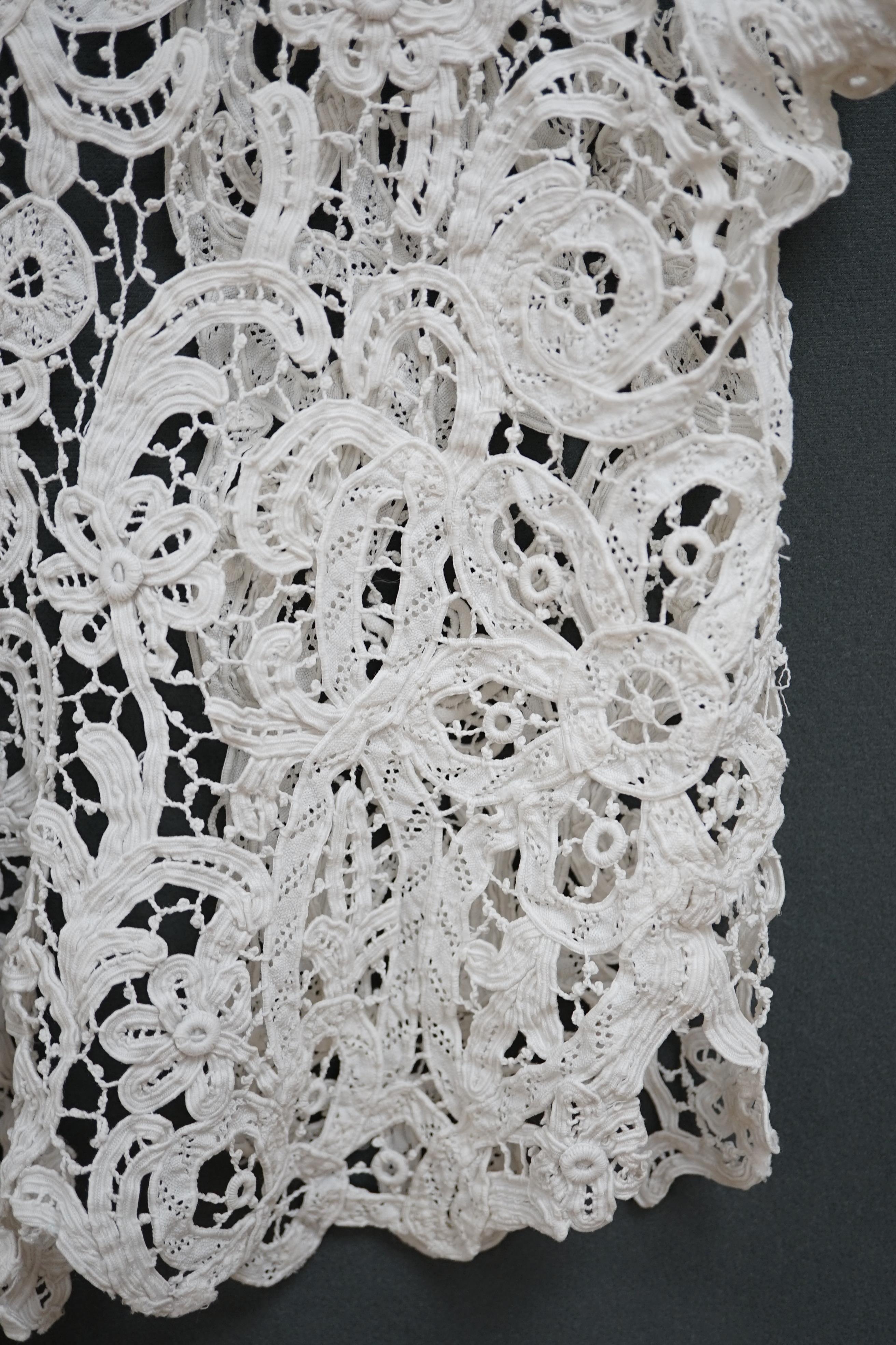 An Edwardian ladies white lace bolero, a tape lace Edwardian cap sleeve bolero with hand sewn bracts, attaching the tape lace together, possibly part of a wedding dress or summer dress, back under arm width 36cm. Conditi